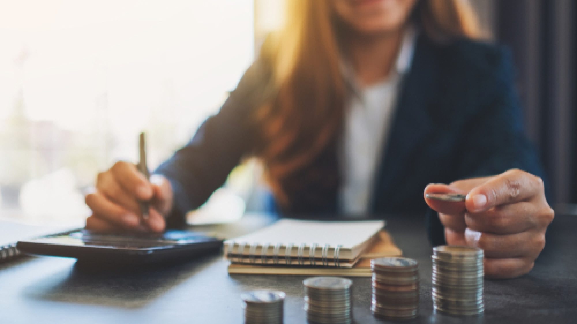 Businesswoman,Holding,And,Stacking,Coins,While,Calculating,Money,On,The