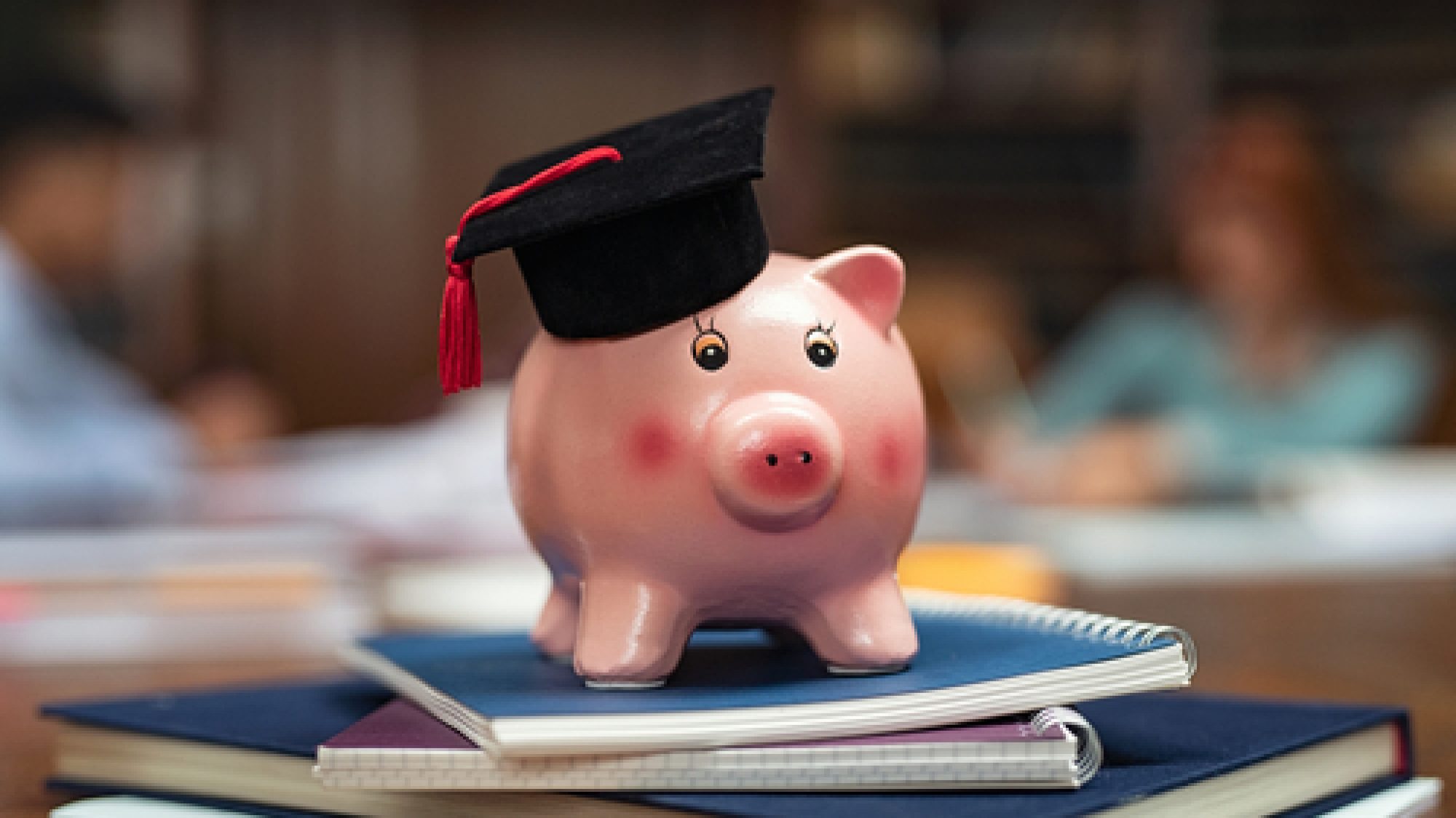 Piggy,Bank,Wearing,Mortar,Board,On,Pile,Of,Books,In