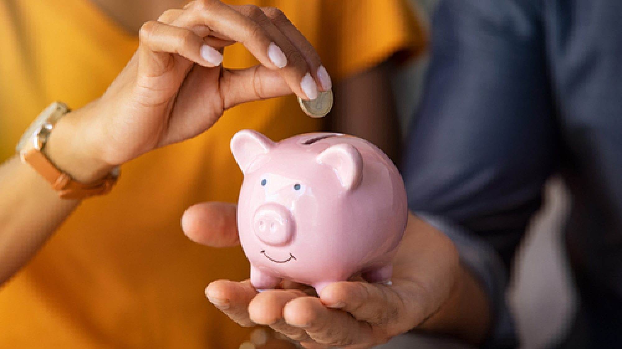 Close,Up,Of,Man,Holding,Pink,Piggybank,While,Woman,Putting
