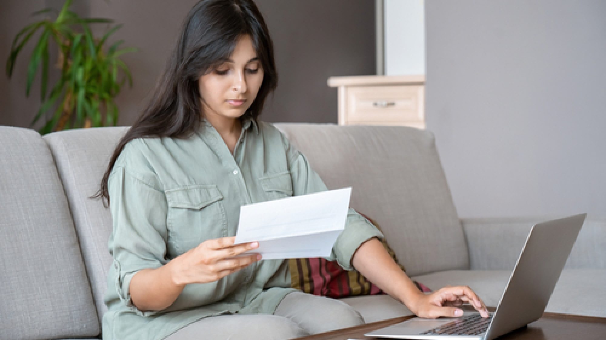 Young,Indian,Woman,Holding,Letter,Using,Laptop,Computer,Application,Paying