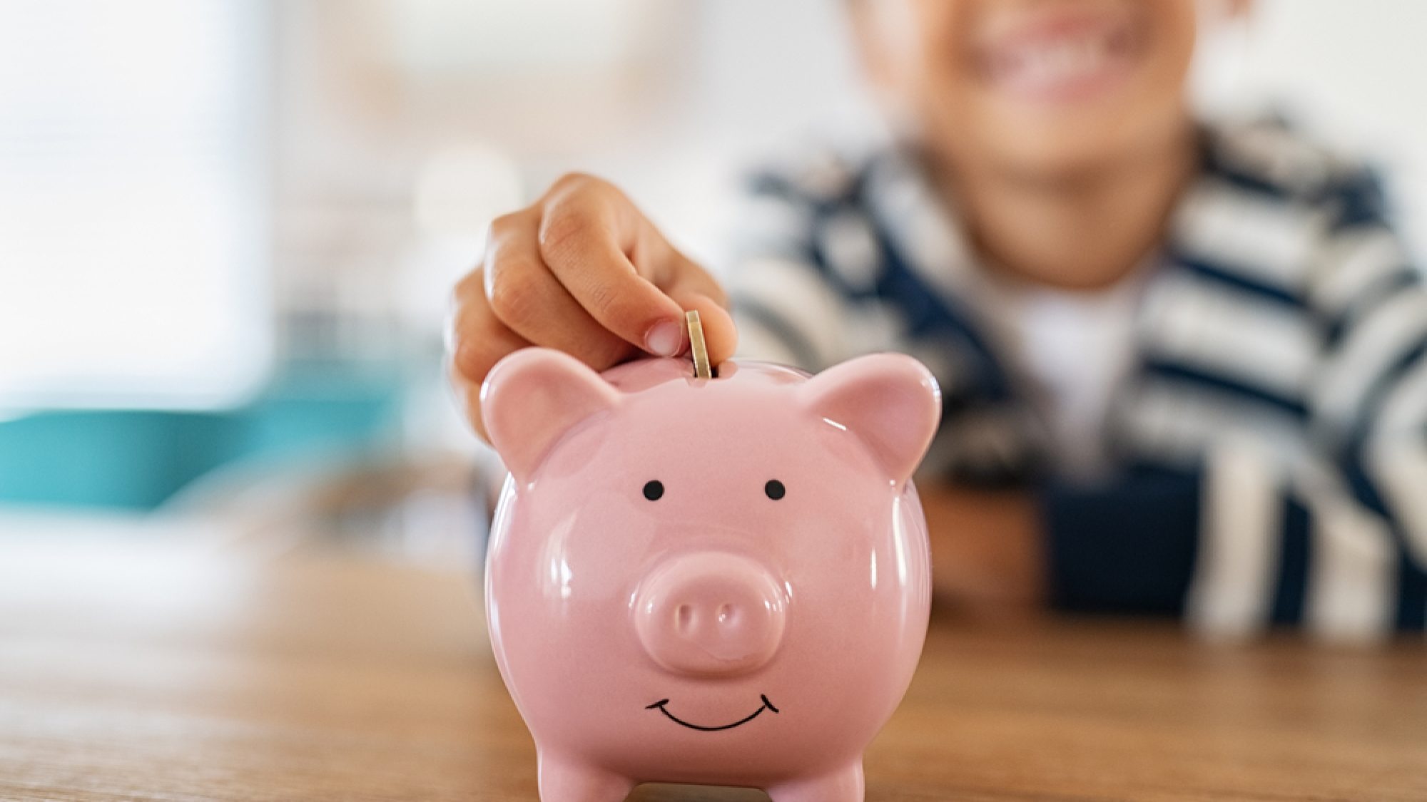 Close,Up,Of,Little,Boy,Saving,Coin,Into,Piggy,Bank
