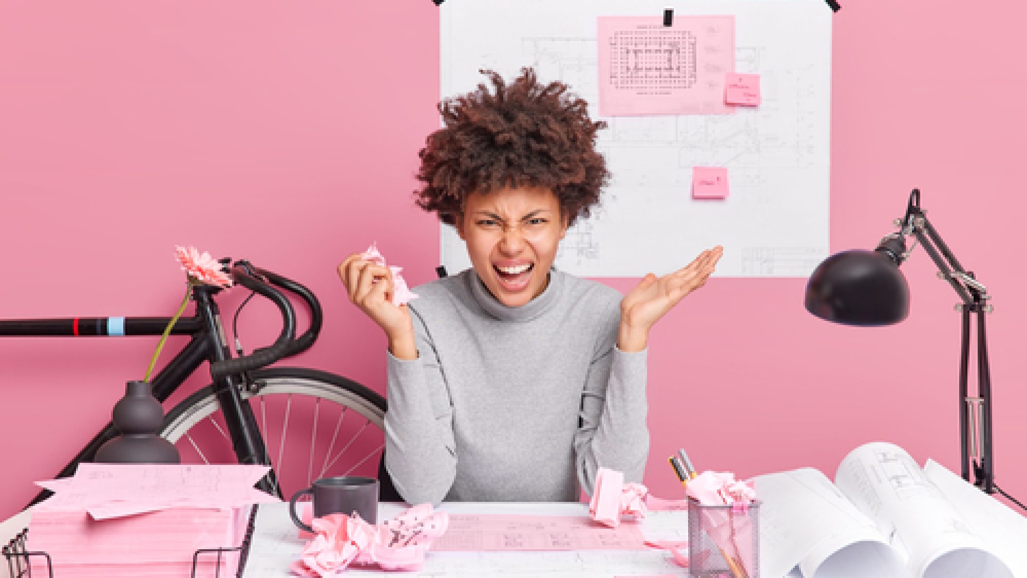 Angry,Female,Architect,Poses,At,Table,With,Papers,Blueprints,And