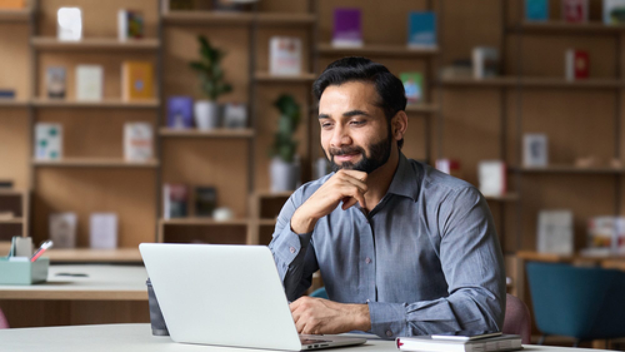 Smiling,Indian,Businessman,Working,On,Laptop,In,Modern,Office,Lobby
