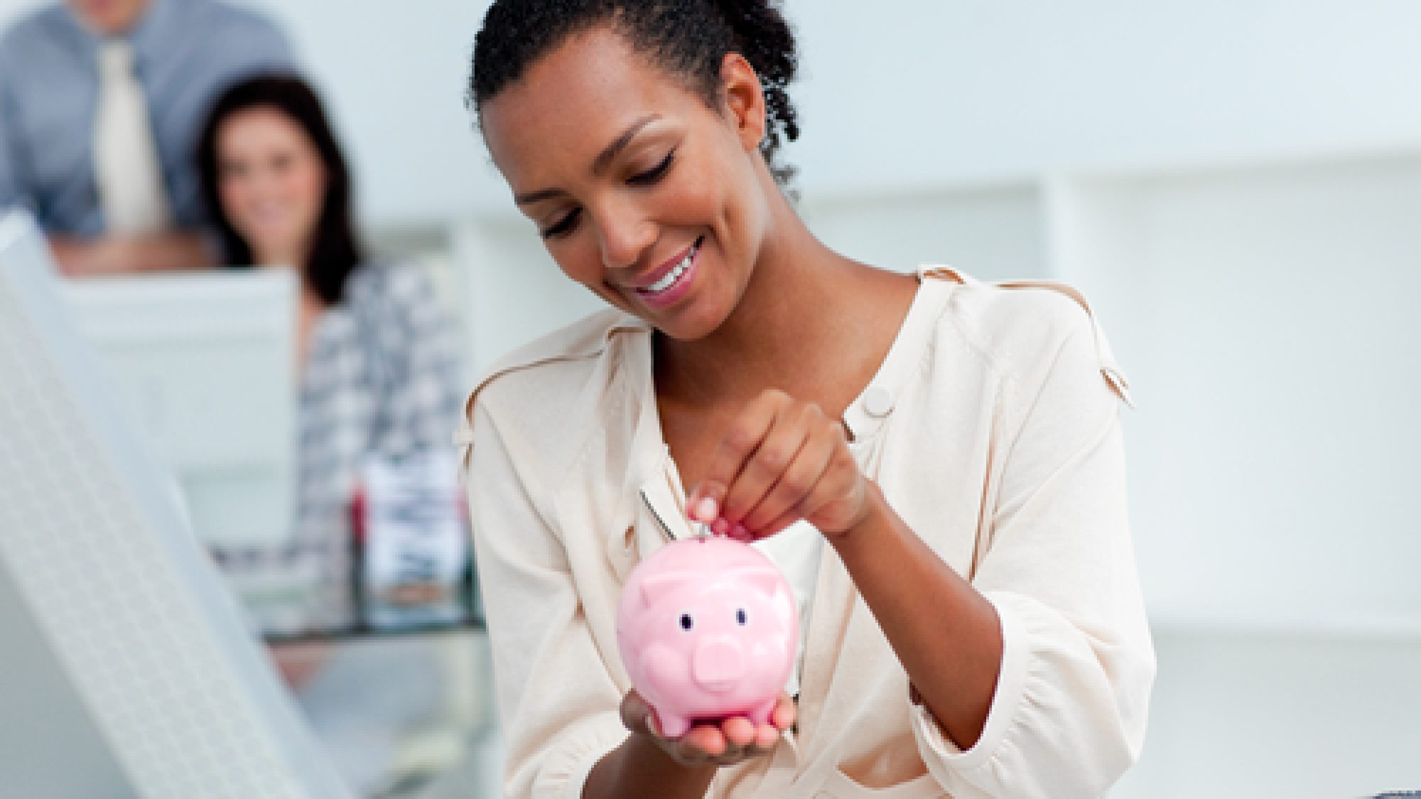 Joyful,Businesswoman,Saving,Money,In,A,Piggy-bank,At,Her,Desk